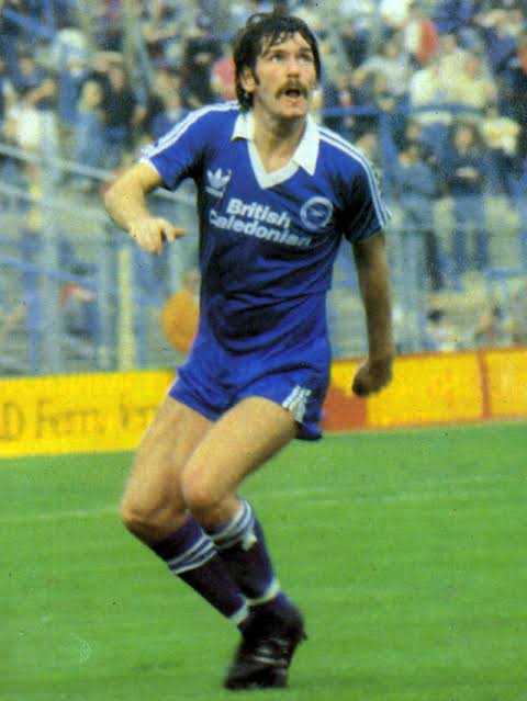 Don Shanks in a blue Brighton shirt running on the pitch in front of a crowded stand